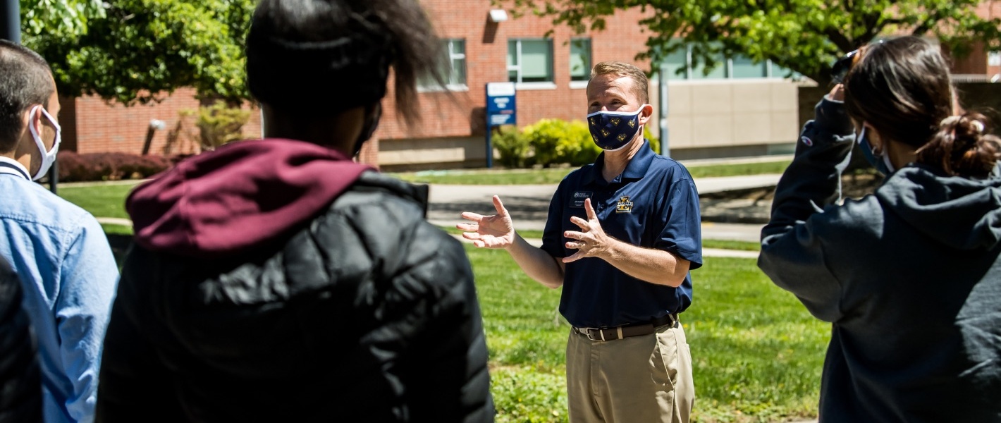 Man wearing medical mask speaks to people outdoors