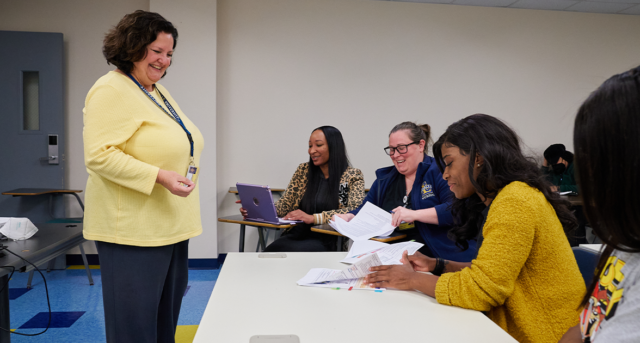 Associate professor Jeannine Uribe, Ph.D., RN, talks with students during a class in Benilde Hall.