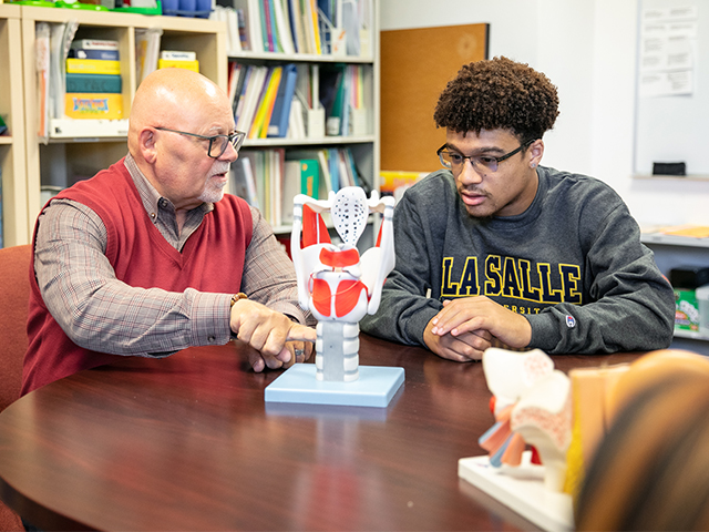 professor and student observing human anatomic 3D model