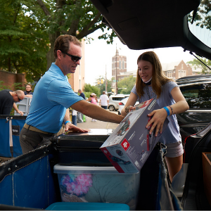 An image of a student and the student's family moving items from a car.