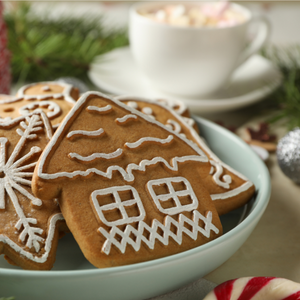 Gingerbread cookies in a bowl with hot chocolate and a candy cane in the background.