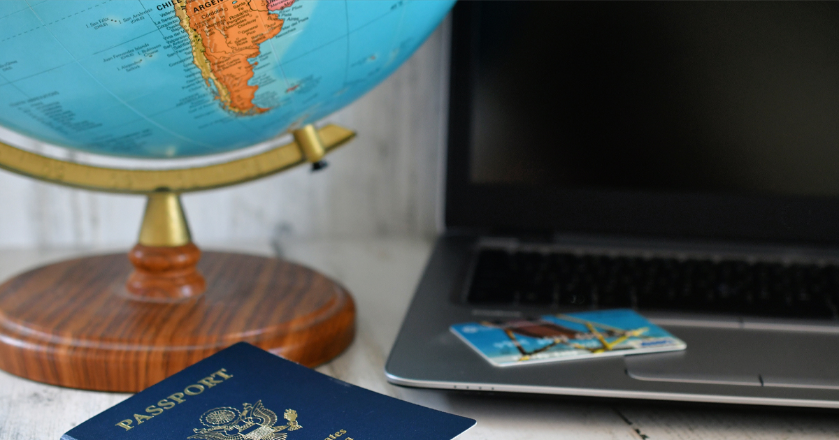Image of a globe, laptop computer and passport.