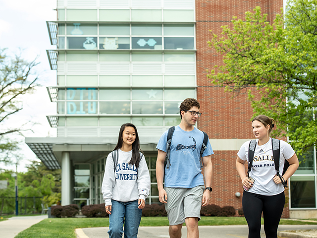 Three students walking in front of the Holroyd Hall Science Building