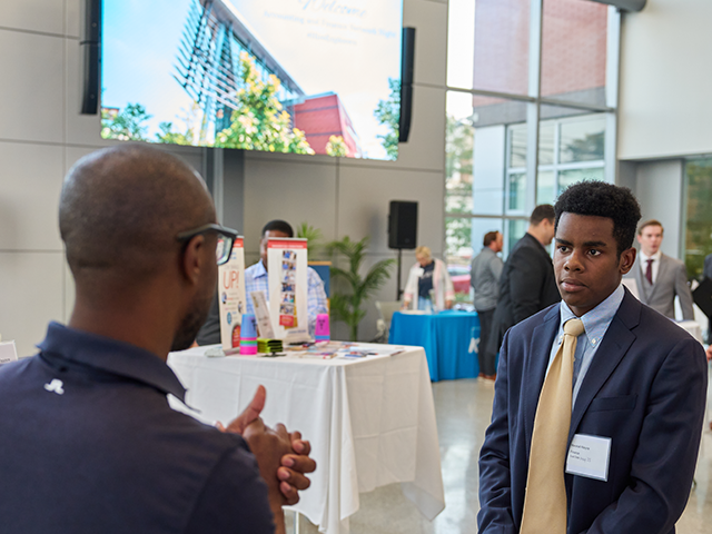 Image of an alumnus speaking with a current male student.