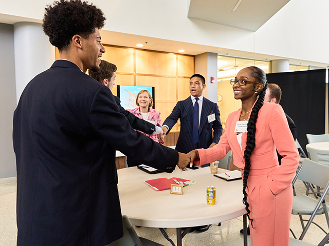 Image of two people shaking hands at a networking event.