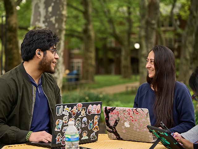 Image of two students sitting on tables at the Hansen Quad.