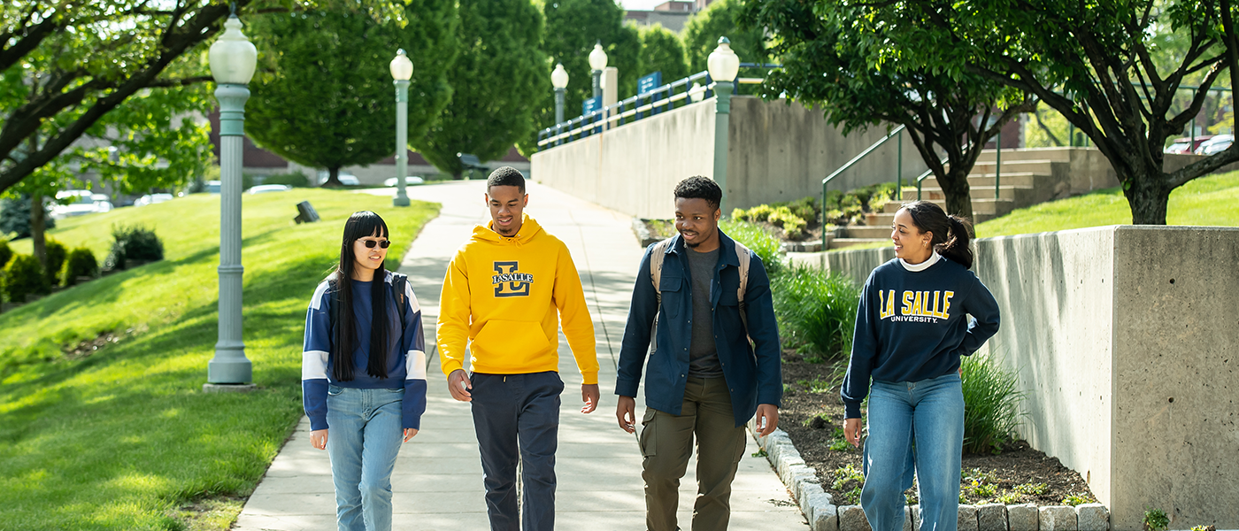 Image of four students walking around campus.