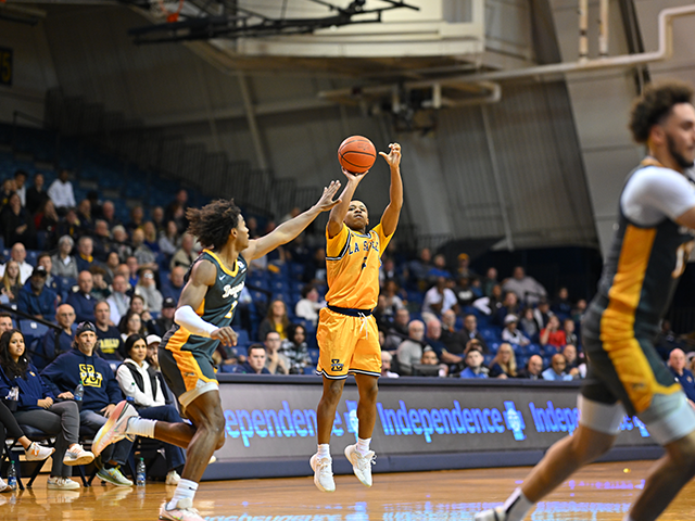 A basketball player shooting the ball as his opponent tries to block it