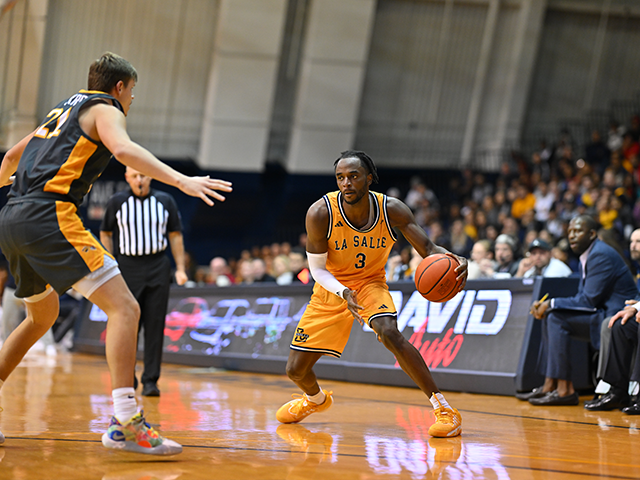 A men's basketball player dribbling the ball and his opponent stands in front of him
