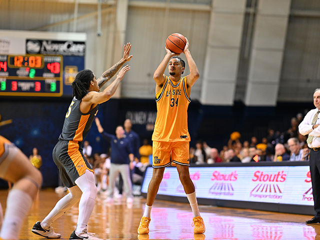 A men's basketball player holding the ball above his head.