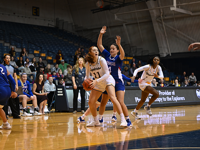 A women's basketball player holding the ball as her teammates run to get open.
