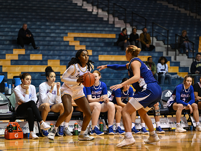 Image of a women's basketball player holding the ball and looking to throw it.