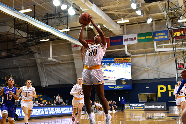 Image of a women's basketball player shooting the ball in the basket.