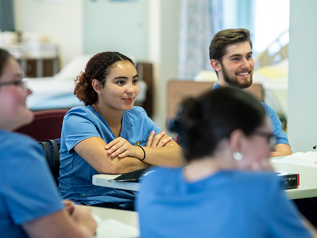 Image of nursing students sitting in a classroom and smiling.
