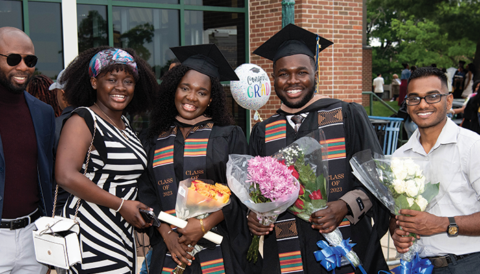 Image of two graduates posing for a photo with their family.