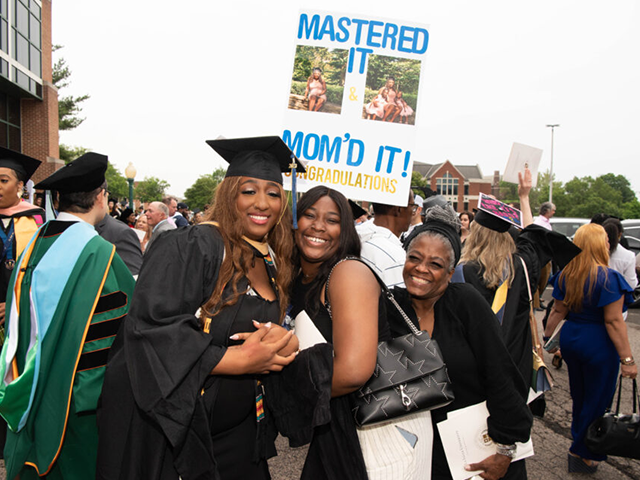 Image of a graduate posing for a photo with her family.