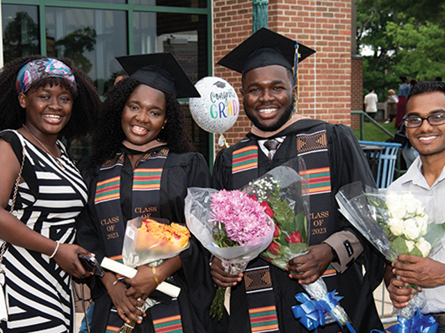 Image of two graduates posing for a photo with their family.
