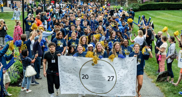 Image of students holding a Class of 2027 sign and walking to the Tom Gola Arena.