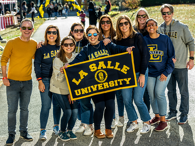 Image of alumni holding a La Salle sign at Homecoming