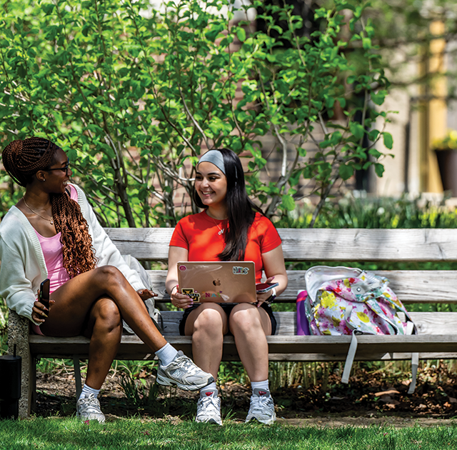 Image of two students sitting on a bench on the Hansen Quad