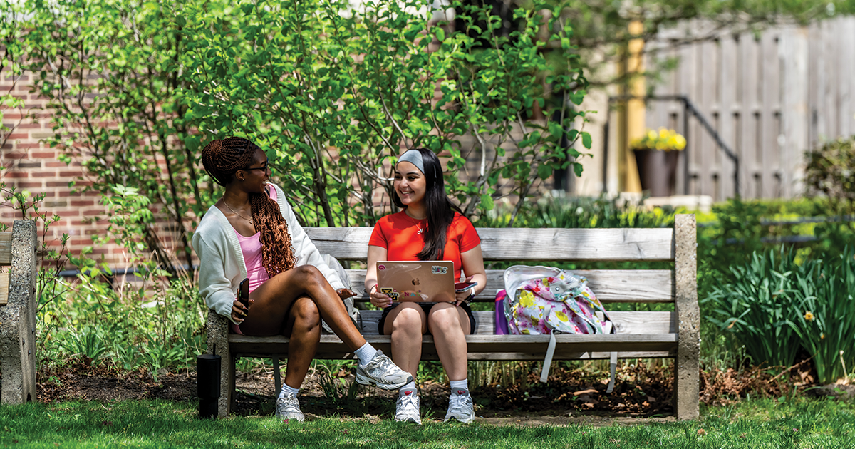 Image of two students sitting on a bench on the Hansen Quad