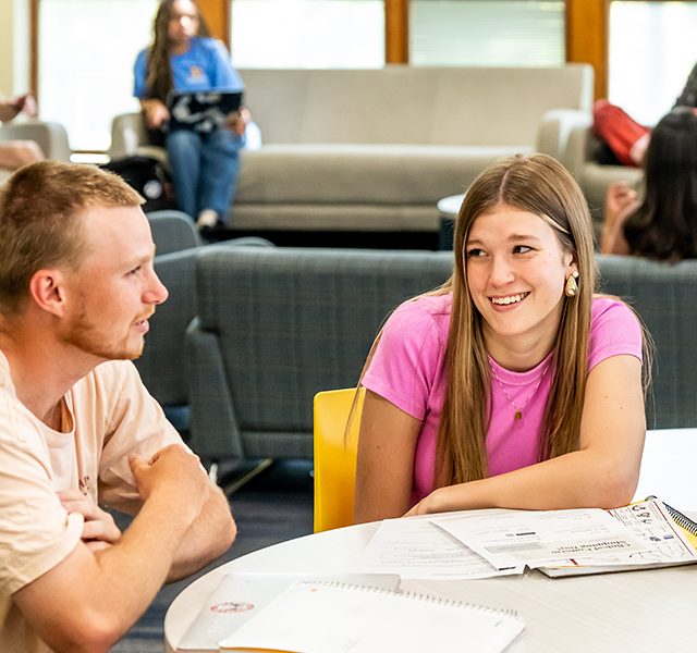 Image of 3 students sitting at a table and talking