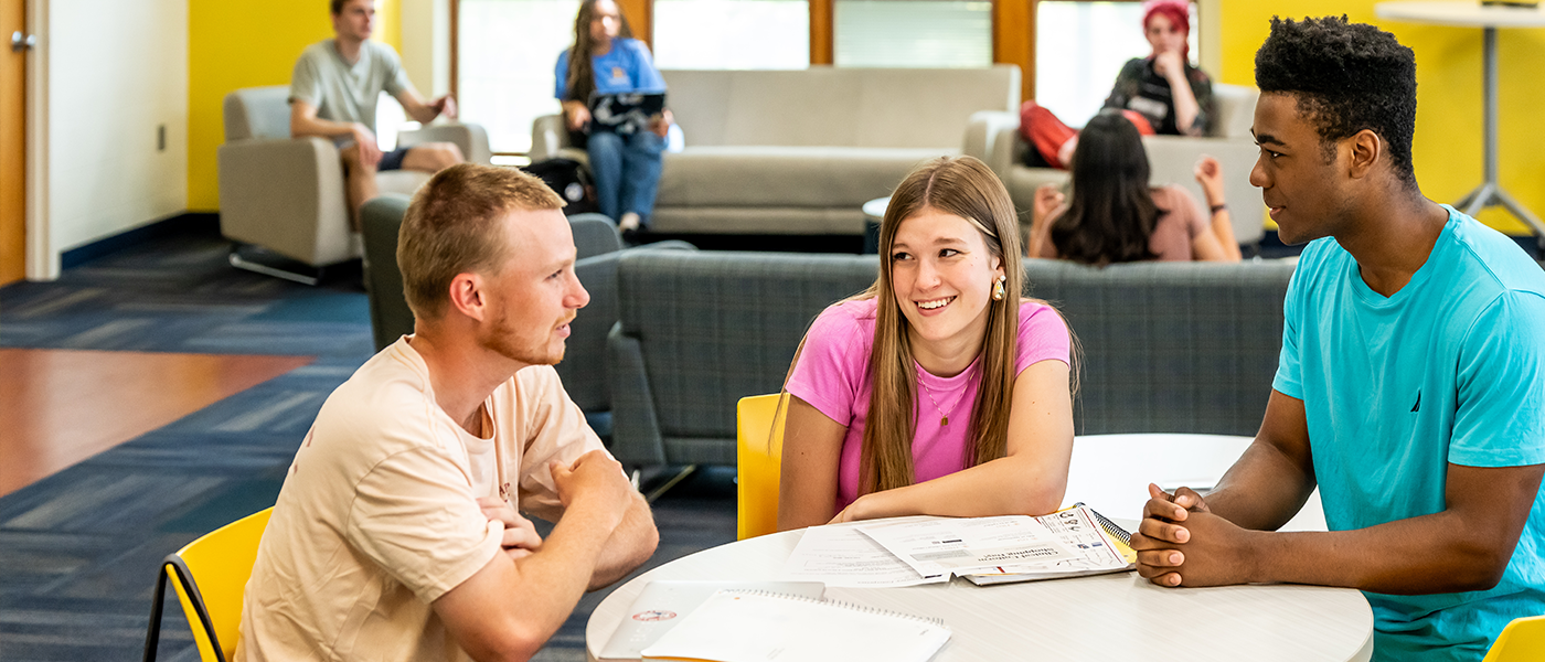 Image of 3 students sitting at a table and talking