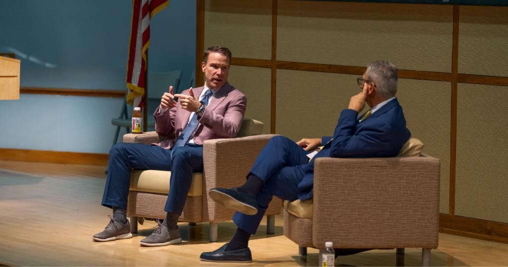 Two men sitting and talking on stage