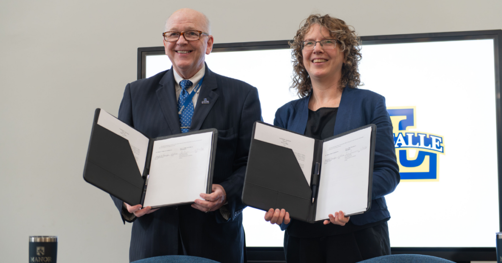 Two people holding signed paperwork