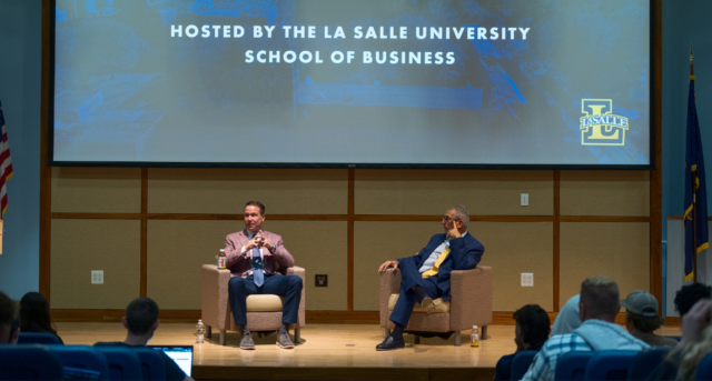 Two men sitting and talking on stage